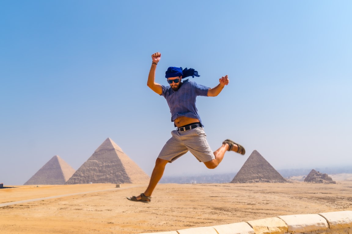A guy jumping in front of Giza Pyramids
